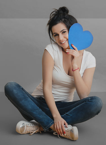 A woman in KSNS shoes, holding a heart-shaped sign in one hand.