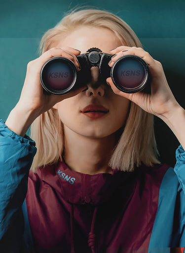 A woman clad in a KSNS jumper uses a telescope to glimpse future fashion trends.